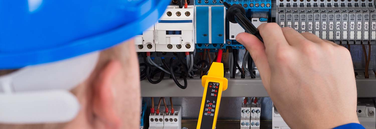 Male Electrician Examining Fusebox With Voltage Tester